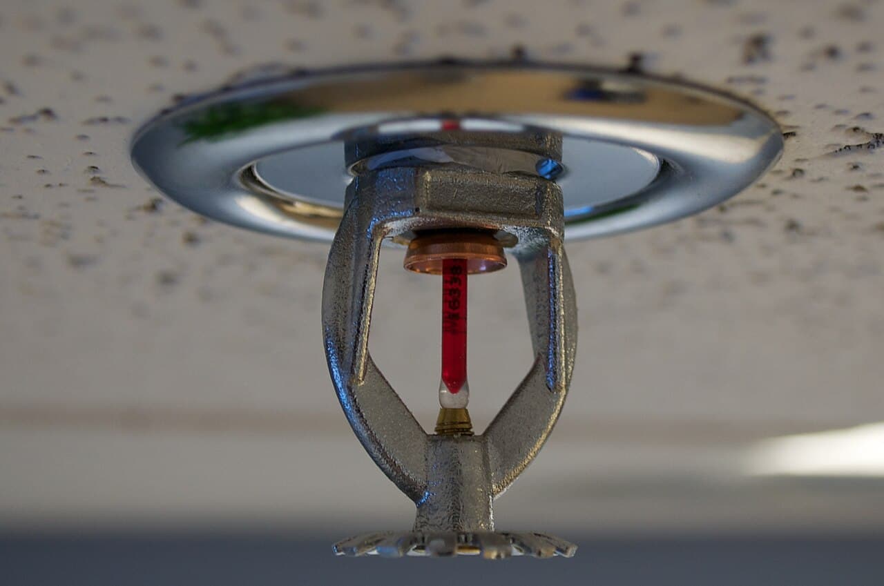 Close-up of a ceiling-mounted fire sprinkler with a red glass bulb